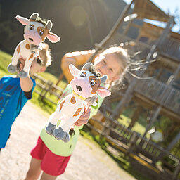 Zwei Kinder zeigen ihre Plüschkühe stolz in die Kamera