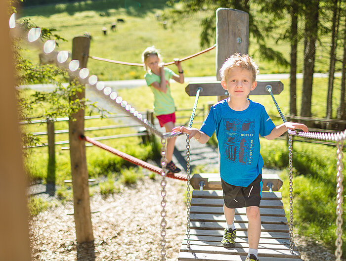 AllesAlm Zwei Kinder spielen auf dem Erlebnisweg Alles Alm