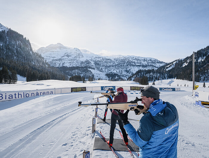Drei Personen beim Zielen mit einer Biathlonwaffer vor der Gnadenalm